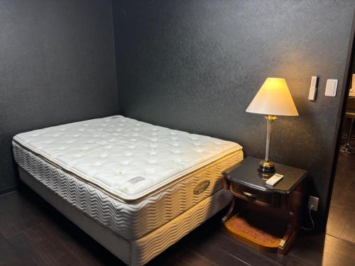 a bed in a room with a lamp on a table at Tokurajyo - Vacation STAY 15813 in Akiruno