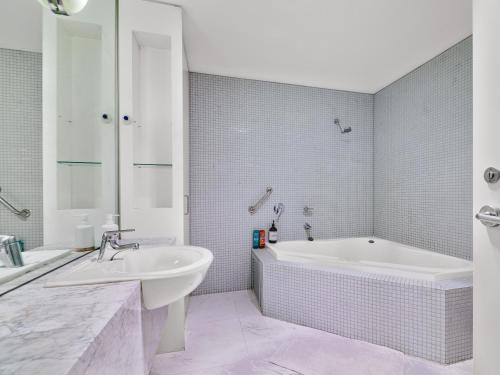een witte badkamer met een bad en een wastafel bij Serenity One Boutique in Melbourne