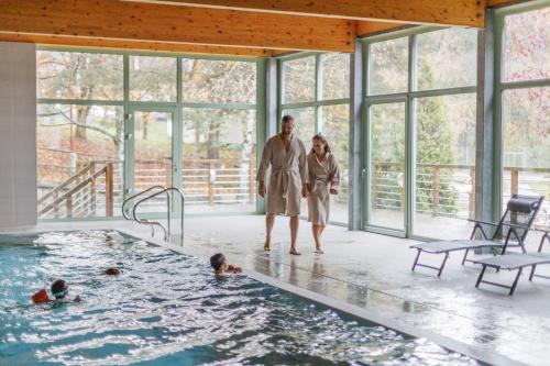 a man and a woman standing in a swimming pool at Hotel Rusava 2 depandance in Rusava