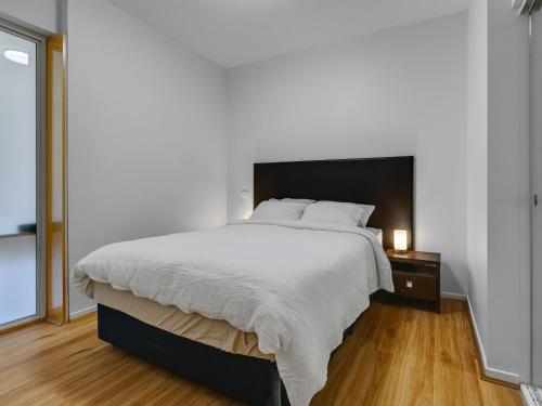 een slaapkamer met een groot bed en een nachtkastje met een lamp bij Serenity One Boutique in Melbourne