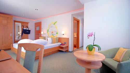 1 dormitorio con cama, sofá y mesa en Samnaunerhof Vital-Hotel, en Samnaun