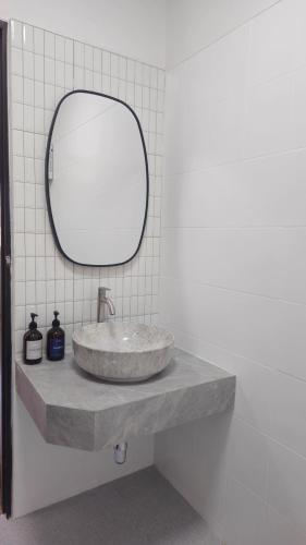 ein Waschbecken mit rundem Spiegel auf der Theke in der Unterkunft 2Bedrooms Beachfront House with Fast WIFI in Nathon Bay