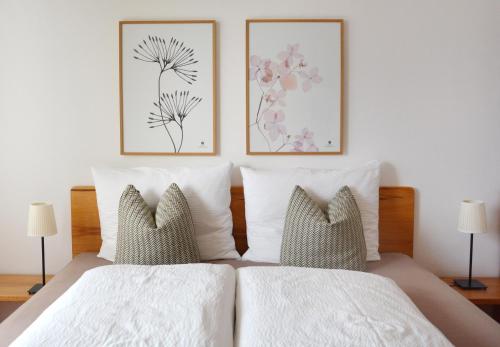 een bed met twee kussens en twee foto's aan de muur bij Appartement Karnutsch in Schenna