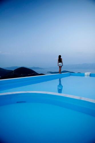 Eine Frau steht am Rand eines Schwimmbeckens in der Unterkunft marmar lefkada luxury villas in Vlikhón