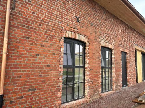 a brick building with three windows on it at Tjusteplekske in Heuvelland
