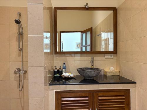 een badkamer met een wastafel en een spiegel bij Beachfront Villa Mawar with Private Pool and Sunset View in Pengastulan