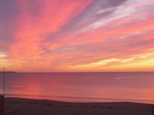a sunset on a beach with the ocean at Les Chants d'Ailes - Hôtel Face Mer in La Turballe