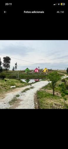 una strada sterrata in un campo con case sullo sfondo di Cabanas paraíso pousadas a Bagé