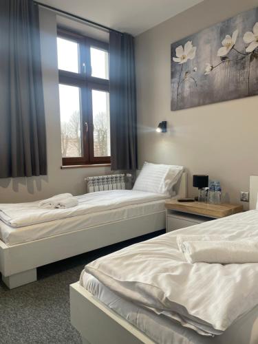two beds in a room with a window at Wielkopolanka Pokoje gościnne i Restauracja in Chodzież