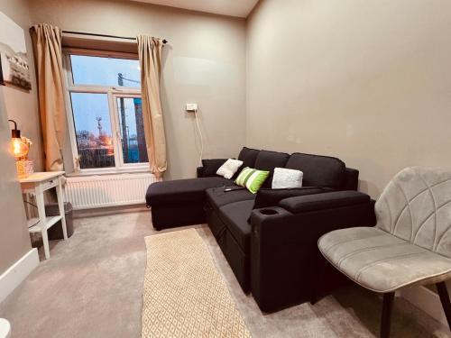 a living room with a black couch and a chair at Flat in Manchester, 2 en-suite Beds, Etihad, Coop in Manchester