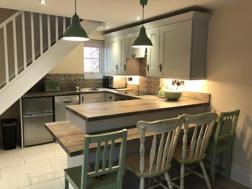 a kitchen with a table and chairs and a staircase at Repton Cottage in the Heart of the Village in Repton