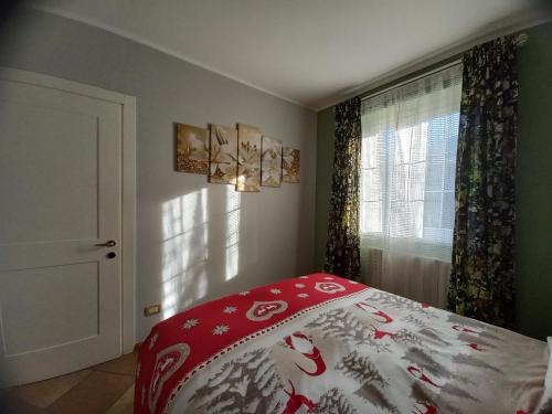 una camera con un letto e un piumone rosso e bianco di Dimora degli Gnomi a Tirano