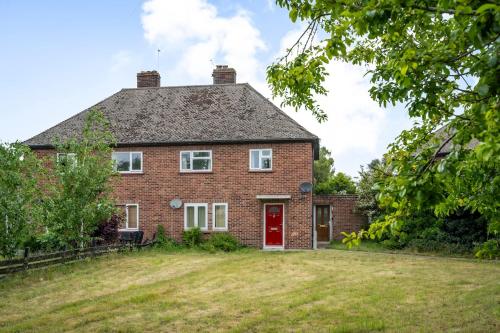 een stenen huis met een rode deur en een tuin bij Keralia in Wivenhoe