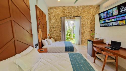 a bedroom with two beds and a desk and a television at Casa María Eulalio - Boutique Guesthouse in Mérida
