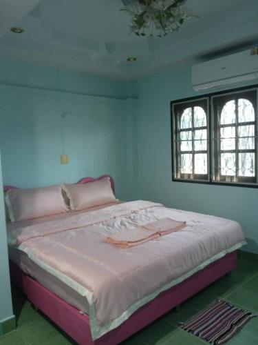 a bedroom with a bed with pink sheets and two windows at Sairung Farmstay and Cawboy Krabi in Ban Nua Khlong