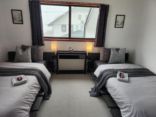 ein Zimmer mit zwei Betten und einer Couch und einem Fenster in der Unterkunft Silver Fox Madarao in Iiyama
