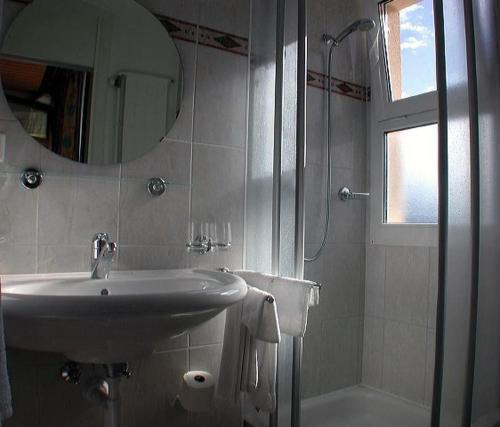 y baño con lavabo, espejo y ducha. en Hôtel de Ville, en Broc
