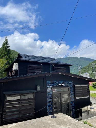 a black house with a garage and mountains in the background at Huis Tashiro in Yuzawa