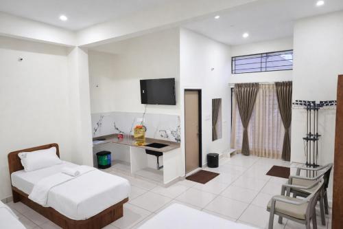 une chambre avec un lit, un bureau et une télévision dans l'établissement Savi Service Apartments, à Chikmagalur