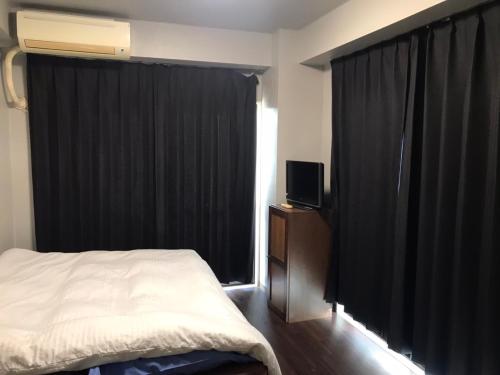a bedroom with a bed and a window with black curtains at LEGALCOURT - Vacation STAY 14717 in Akiruno