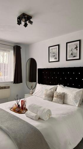a bedroom with a large white bed with a black headboard at Modern 2-Bed Flat, Spacious, near Harry Potter Studio in Watford
