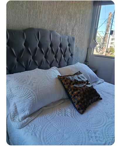 a bed with a gray headboard and a pillow and a window at Lindo Por do Sol, Quarto casal com Banheiro privativo, casa compartilhado in Pato Branco