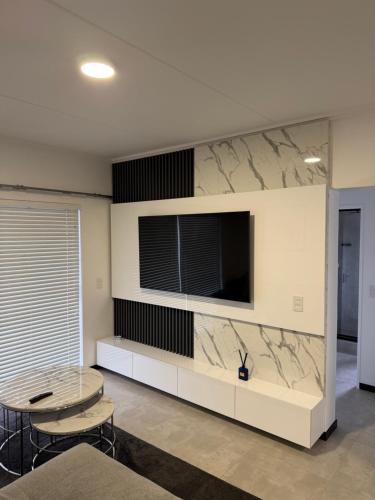 een woonkamer met een tafel en een tv aan de muur bij The Grey Luxe Suite in Sandton
