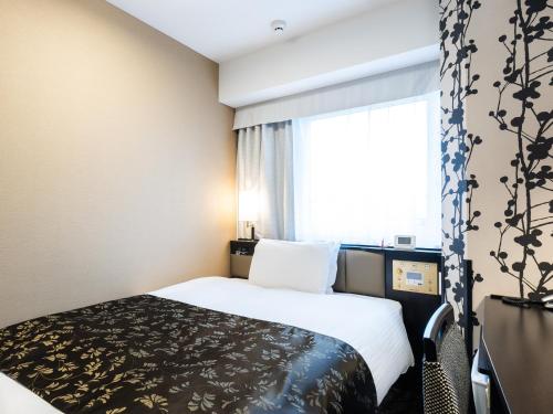 a hotel room with a bed and a window at APA Hotel Shin Osaka Minamikata Ekimae in Osaka