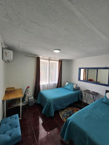 a room with two beds and a table and a desk at Shalom_MatSofy in Santiago