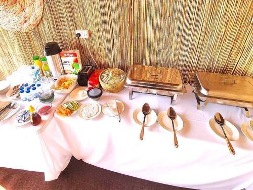 een tafel met keukengerei en borden met eten erop bij Beach Moments Camp in Aḑyūḩ