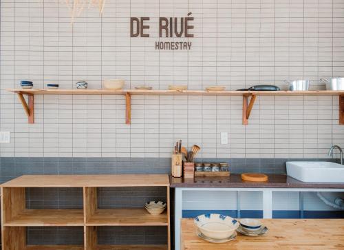 eine Küche mit Holzregalen an einer weiß gefliesten Wand in der Unterkunft De Rivé Homestay Cần Thơ in Cần Thơ