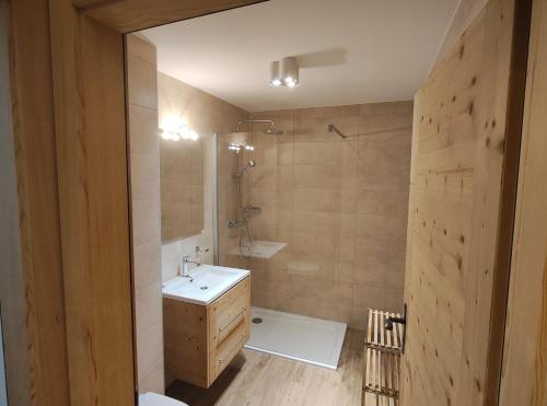 een badkamer met een witte wastafel en een douche bij Chalet l'O - Charm and Modernity in Leytron