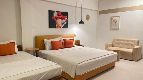 una stanza d'albergo con due letti e una sedia di A Day Rayong a Ban Pa Khan