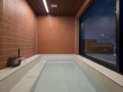 een badkamer met een bad en een groot raam bij Staykor Busan in Pusan
