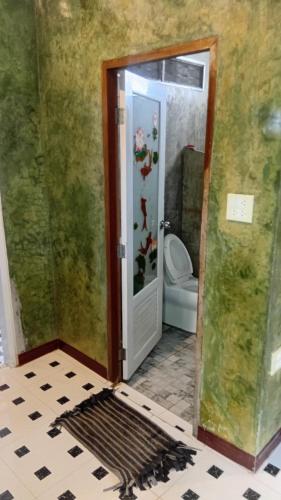 a bathroom with a toilet and a door to a room at Turtle beach Bar 1 Bedroom in Thai Muang