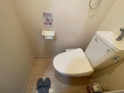a bathroom with a toilet and a sink and blue slippers at Canaan Chuocho Building A in Kagoshima
