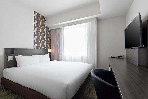 ein Schlafzimmer mit einem weißen Bett und einem Fenster in der Unterkunft Sotetsu Fresa Inn Kitahama in Osaka
