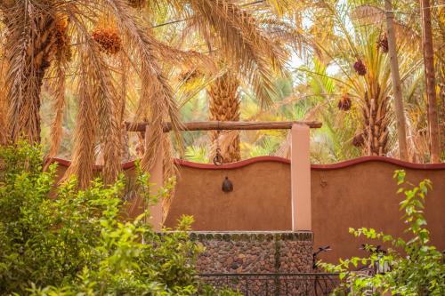 a house with a fence and palm trees at Riad Soleil du Monde in Zagora
