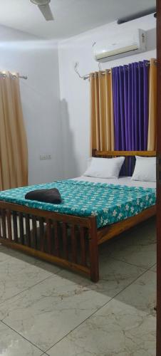 a large wooden bed with a green blanket on it at Grape Garden in Varkala