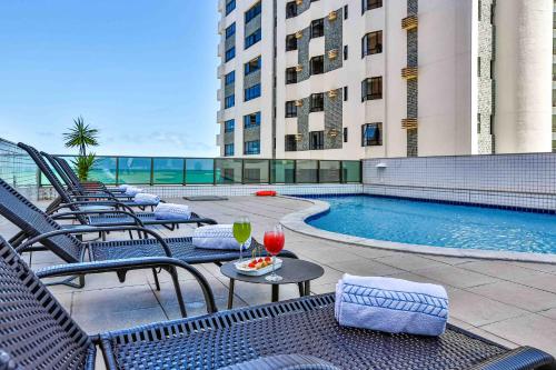 a hotel patio with chairs and a swimming pool at Flat Beach Class Executive - Beira Mar de Boa Viagem in Recife