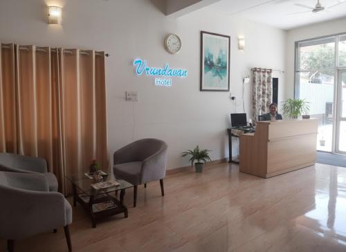 Eine Frau, die an einem Schreibtisch im Wartezimmer sitzt. in der Unterkunft Vrindavan Hotel and Restaurant in Malavli