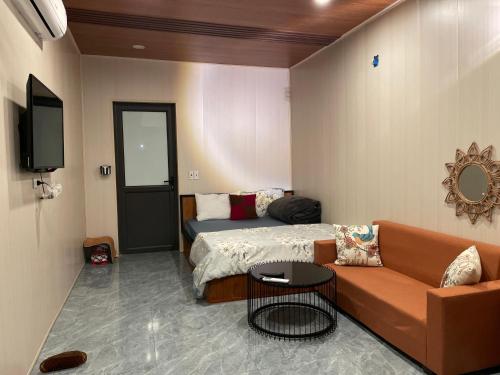 ein Schlafzimmer mit einem Bett, einer Couch und einem Fernseher in der Unterkunft Mộc Homestay - Mộc Châu in Mộc Châu