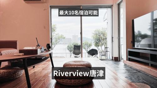 a living room with a desk and a table and a window at Riverview唐津 in Karatsu
