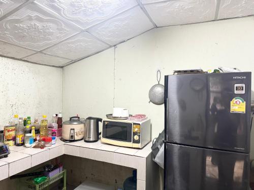 a kitchen with a refrigerator and a microwave on a counter at Stay Like a Local เต็นท์บ้านเรา in Chiang Mai