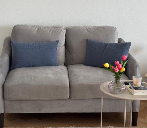 een bank met twee blauwe kussens en een tafel met bloemen bij Fribourg Studio Home in Fribourg