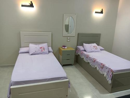two beds in a bedroom with a mirror and lights at noreno houseاسوان شياخة تانية طريق السادات in Aswan