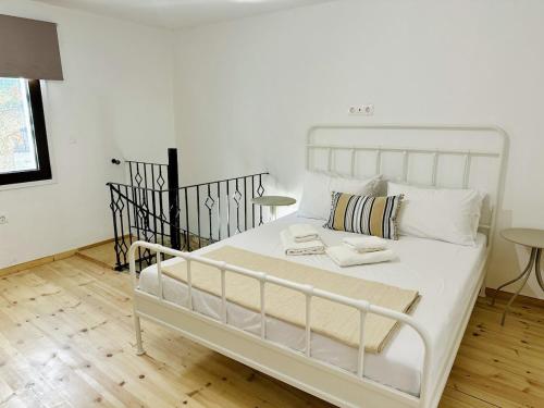 un letto bianco in una stanza bianca con due tavoli di Nomas Home Kalyves a Kalyves