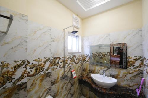 Un baño con lavabo y paredes de mármol. en Gold Max Hotel, en Lahore