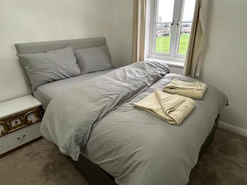 a bed with two towels on it in a bedroom at Chartsworth 4 Bedrooms Spacious House in Harold Wood