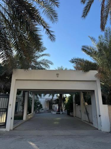 eine weiße Garage mit einem Tor und Palmen in der Unterkunft Nizwa heart garden home in Nizwa
